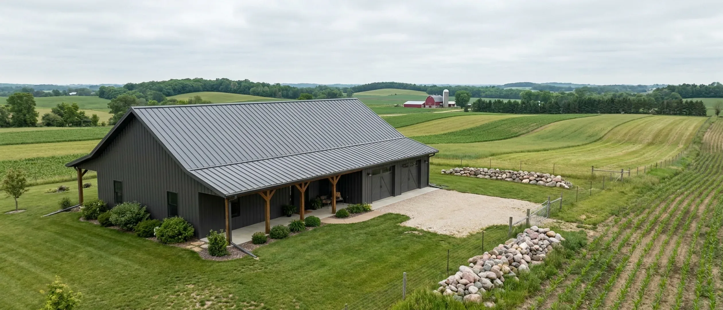 A completed barndominium with a covered entry porch and an attached shop bay, photographed in flat overcast daylight.